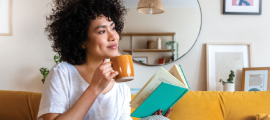 smiling woman reading and holding cup